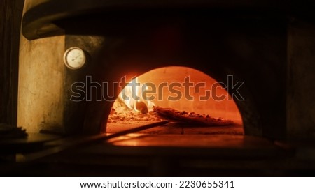 In Restaurant Pizza Peel Transferring Pizza into Wood Fire Stone Oven. Traditional Cooking, Italian Family Recipe. Authentic Pizzeria with Delicious Organic Food. Cinematic No People Shot