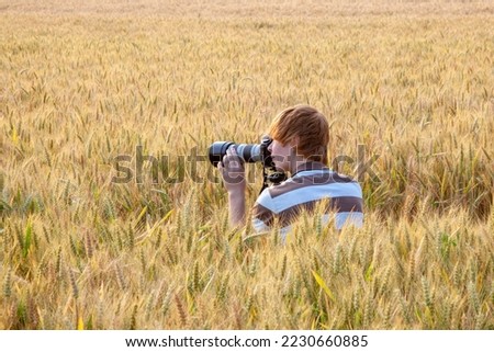 teenage boy taking pictures with tripod in corn field