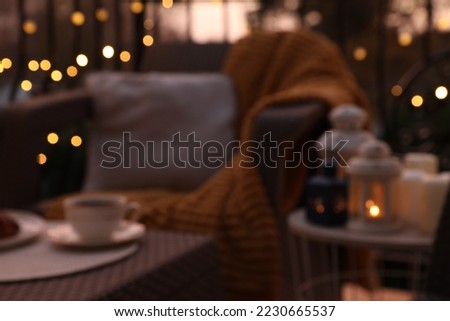 Blurred view of garden furniture with pillow, soft blanket and coffee at balcony
