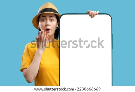 Digital advertising and social media. Amazement young Caucasian attractive woman wearing straw hat holds large smartphone with mock up. Copy space. Concept of website template