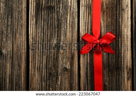 Red ribbon with bow on brown wooden background