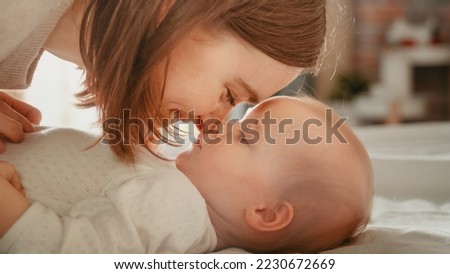 Close Up of a Happy Mother Playing with a Cute Newborn Baby. Mom Bonding with a Toddler, Rubbing Belly, Kissing Nose. Concept of Childhood, New Life, Motherhood.