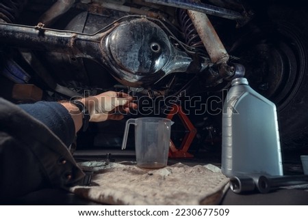 Changing the oil in the front differential of an off-road vehicle, truck with four-wheel drive. Car service. Tools and spare parts. Male hands, mechanic. View from the first person Royalty-Free Stock Photo #2230677509