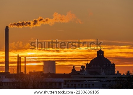 View over the roofs of Nuremberg in Germany during an orange sunset, with view of the opera house and the local power plant with its steaming chimneys