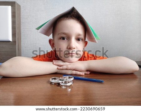 Tired boy with ADHD is bored in class, distracted, does not want to do homework. Therapy for ADHD children. Spinner and children with ADHD. Attention deficit and hyperactivity in children, neuropsycho Royalty-Free Stock Photo #2230690659