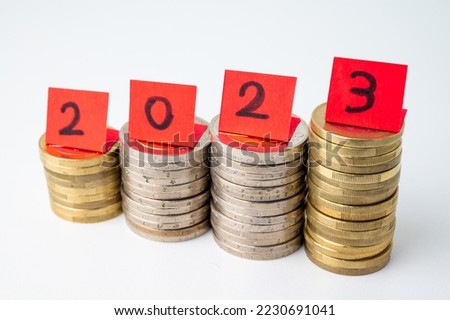 Stacks of coins, and red tickets that make up the number 2023. Arrival of 2023 and prospects for the new year.