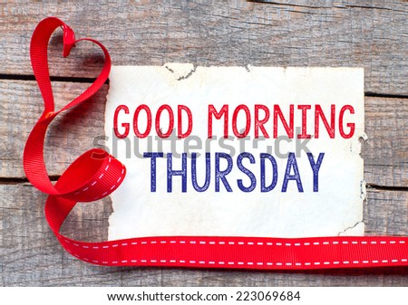 Good Morning Thursday. White card with text Good Morning Thursday on wooden table, with red ribbon 