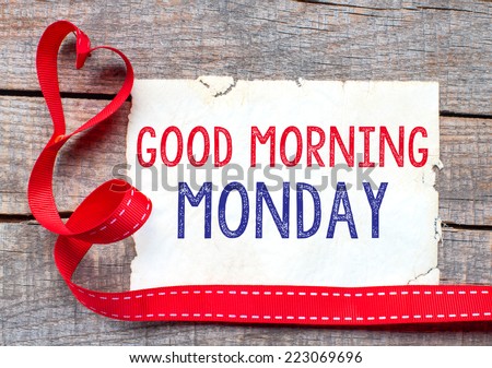 Good Morning Monday. White card with text Good Morning Monday on wooden table, with red ribbon 