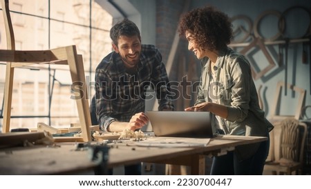 Excited Young Man and Woman Using Laptop Computer, Discussing a Successful Project in a Carpentry Studio. Furniture Designers High Five and Celebrate Receiving a Big Business Opportunity. Royalty-Free Stock Photo #2230700447