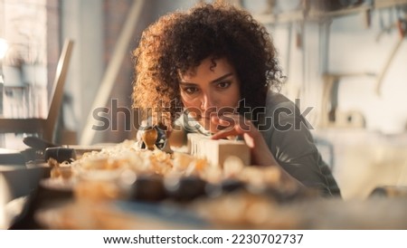 Close Up Portrait of a Young Female Artisan Carpenter Using Hand Plane to Shape a Wood Bar. Beautiful Artist Working on a Project in a Woodworking Workshop. Royalty-Free Stock Photo #2230702737