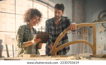 Excited Young Man and Woman Using Tablet Computer, Discussing a Successful Project in a Carpentry Studio. Furniture Designers Working in Loft Studio.