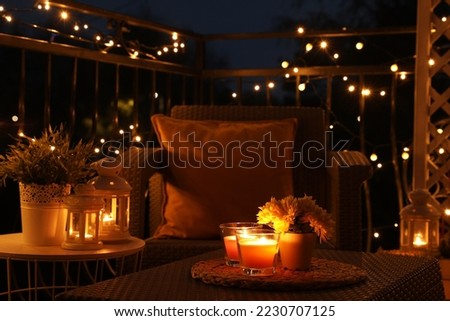 Beautiful view of garden furniture with pillow and burning candles at balcony Royalty-Free Stock Photo #2230707125