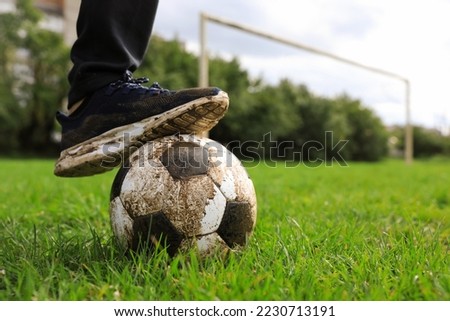 Man with dirty soccer ball on green grass outdoors, closeup. Space for text
