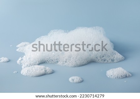 Fluffy bath foam on light blue background Royalty-Free Stock Photo #2230714279