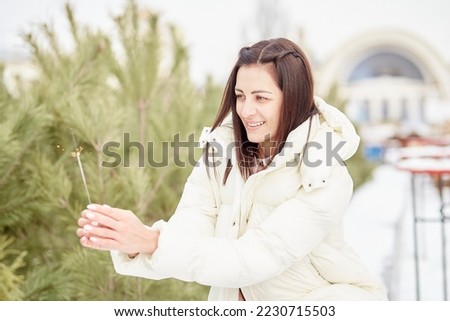 Attractive smiling woman with Christmas bengal light outdoor. Christmas decorations, winter holidays.