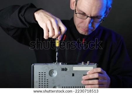 repair of an old satellite tuner by person on the table and gray background