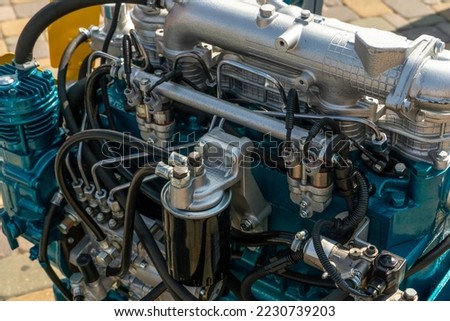 A new modern car engine on the street. The concept of a modern powerful automobile engine for heavy industrial machinery. Mechanical parts of the motor close-up.