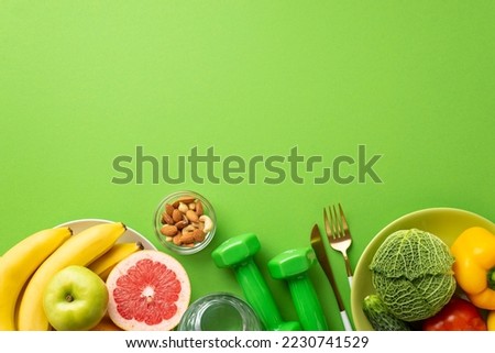 Proper diet concept. Top view photo of plates with fruits and vegetables nuts cutlery glass of water and dumbbells on isolated green background with copyspace Royalty-Free Stock Photo #2230741529
