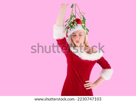 Caucasian woman wearing santa costume holding a mistletoe against copy space on pink background. christmas festivity concept