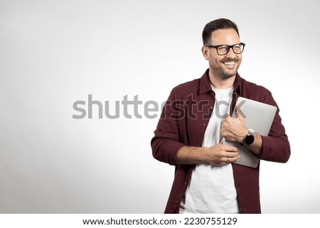 Casual dressed business man holding and using laptop. Picture taken in studio on white background