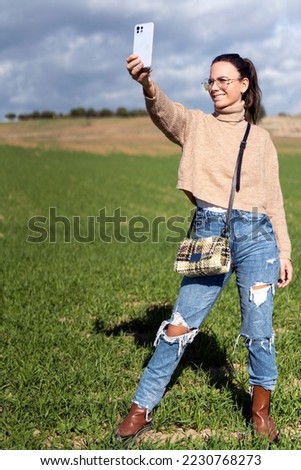 Smiling woman taking selfie while standing on grass