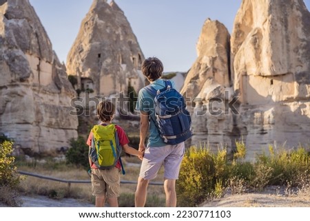 Father and son tourists on background of Unique geological formations in Love Valley in Cappadocia, popular travel destination in Turkey. Traveling with children in Turkey concept Royalty-Free Stock Photo #2230771103