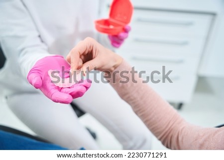 Woman takes a special mouthguard from hands of an orthodontist Royalty-Free Stock Photo #2230771291