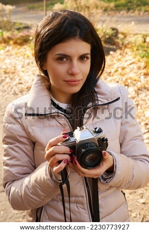 Beautiful dark-haired woman holds a camera in her hands