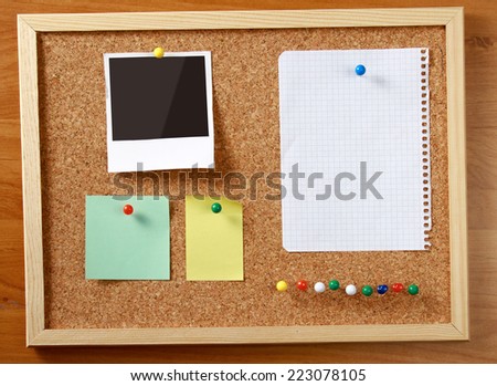 Cork message board with various paper notes.
