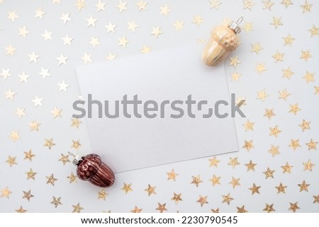 Christmas or New Year card with an empty space for text. Golden shining stars. Toys made of glass in the shape of acorns are on a white background, High quality horizontal photo like a postcard