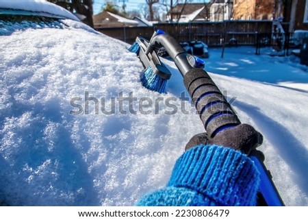 Cleaning snow off windshield perspective picture from point of view of person cleaning with long handled brush - selective focus - room for copy