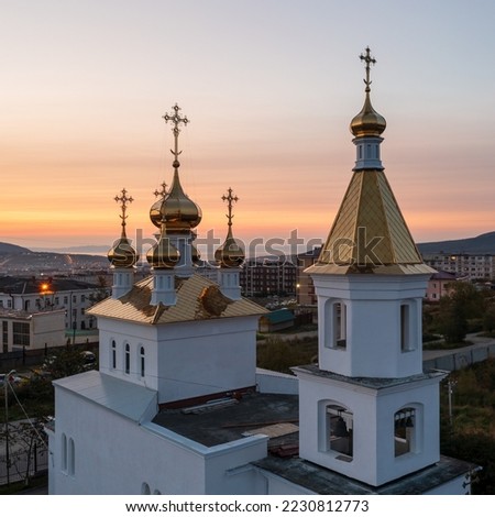 Aerial view of the church with golden roofs, domes and crosses. Bell tower close-up. Dawn. Morning cityscape. Church of Saint John the Baptist, city of Magadan, Magadan region, Far East of Russia.