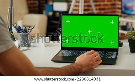 Man using wireless pc with isolated greenscreen display, working on software with chroma key mockup template. Analyzing blank copyspace background on personal laptop at home. Close up.