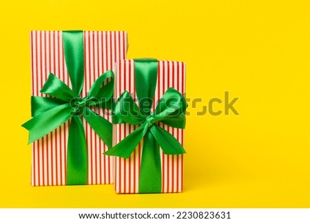 Gift boxes with green ribbon bow on color background.
