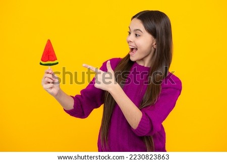 Excited face. Teen girl hold lollipop caramel on yellow background, candy shop. Teenager with sweets suckers. Amazed expression, cheerful and glad.