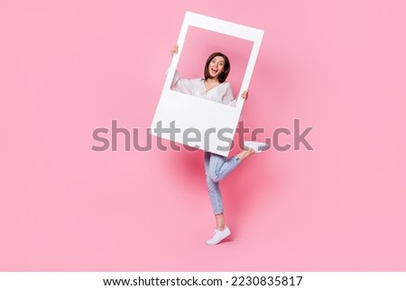 Full length photo of positive pretty lady hand hold white paper image border good mood stand empty space isolated on pink color background