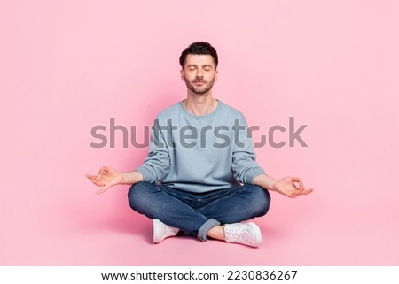 Full body photo of nice young guy sitting floor meditating relaxing worker dressed trendy blue garment isolated on pink color background