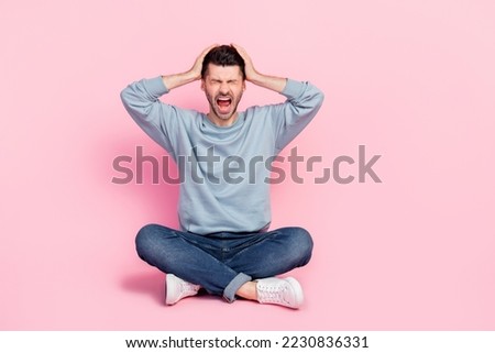 Full length photo of attractive young guy sit floor hands touch hand screaming dressed trendy blue outfit isolated on pink color background Royalty-Free Stock Photo #2230836331