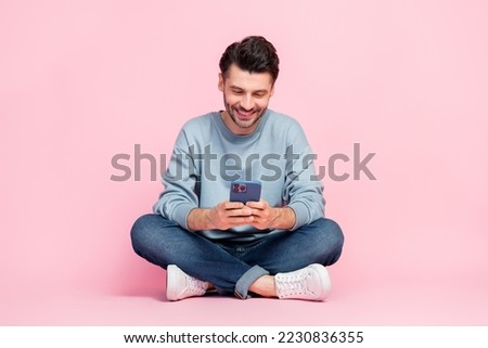Full size photo of handsome young guy holding device reading news write post dressed trendy blue garment isolated on pink color background