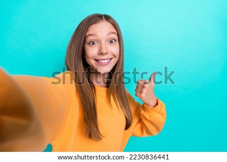 Closeup selfie photo shot of young beautiful brown hair teenager popular blogger girl like sign new cafe isolated on cyan color background