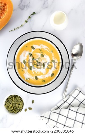 Creamy pumpkin and carrot soup with pumpkin seeds and fresh thyme on a white background. Top view. Food background. High quality photo