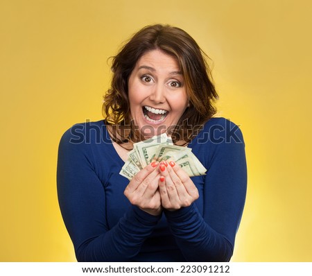 Closeup portrait super happy excited successful middle aged business woman holding money dollar bills in hand isolated yellow background. Positive emotion facial expression feeling. Financial reward