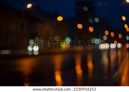 Blurred view of city street with lights at winter rainy night. Bokeh lights background. Abstract artistic photography.