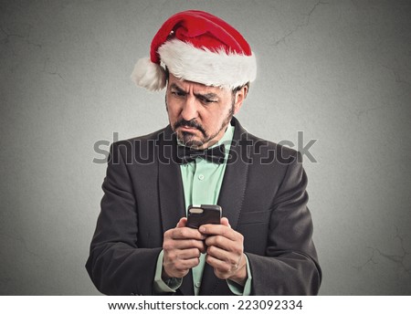 Portrait surprised skeptical funny business man wearing red santa claus hat looking at smartphone discovered online deal to good to be true. Emotion facial expression body language. Holiday season