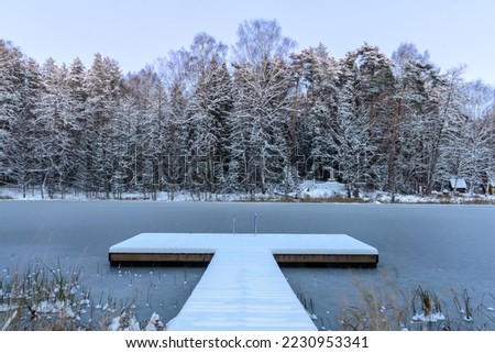 Frozen lake in winter, swimming platform, dock covered with first snow. Royalty-Free Stock Photo #2230953341