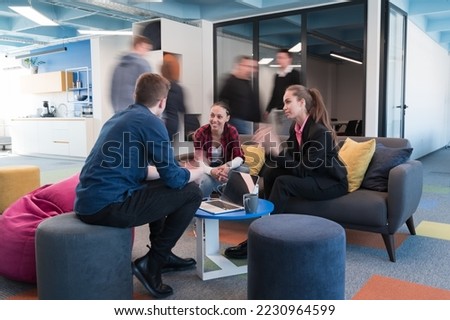 Multiethnic startup business team on meeting in a modern bright open space coworking office. Brainstorming, working on laptop. Group of coworkers walking around in motion blur.
