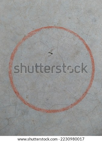 sketching a circle on surface with shattered brick or chalk. Round shape picture has been made on the ground with a piece of brick. Drawing of red circle is being made by drawing a line on the ground.