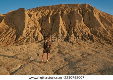 a young woman with long blond hair in a hat on a background of high sandy rocks. beautiful nature. natural background