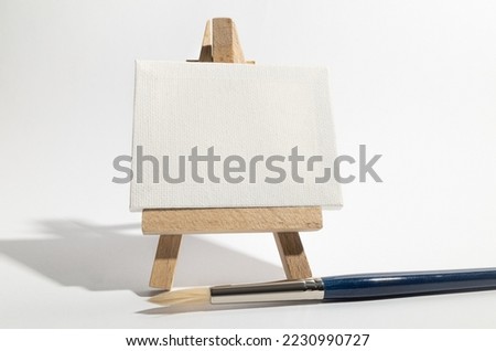 Small wooden easel with blank canvas and paint brush.
