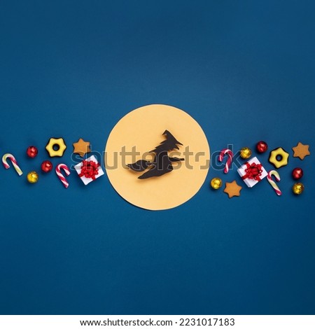 Italian Epiphany day or Dia da Reyes Magos tradition. Witch Befana flying on broomstick, moon, stars and christmas sweets on dark blue background. Top view, copy space. Winter holiday card concept. Royalty-Free Stock Photo #2231017183